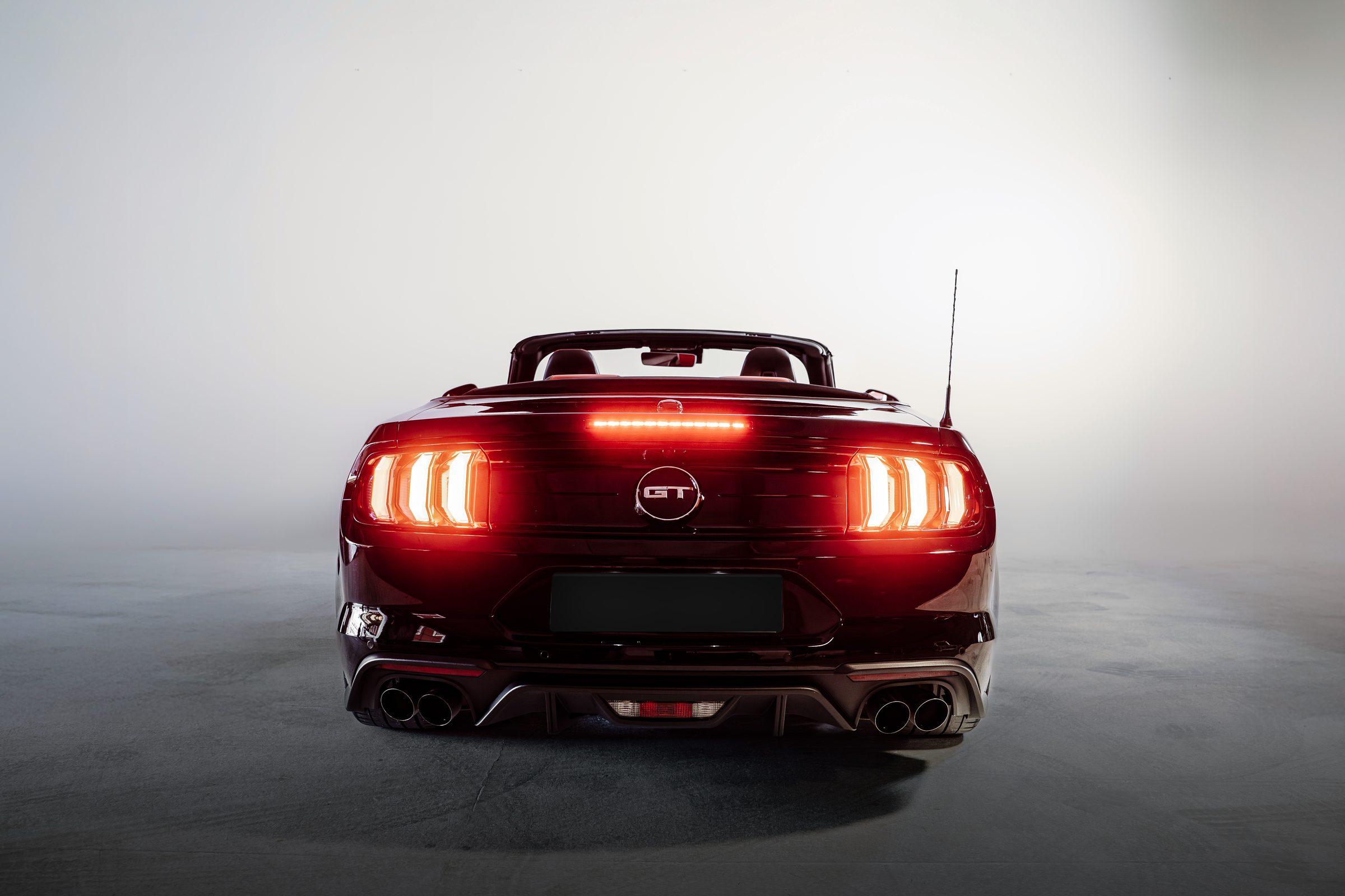Heck des Ford Mustang GT Cabrio mit leuchtenden Rückleuchten im Studio